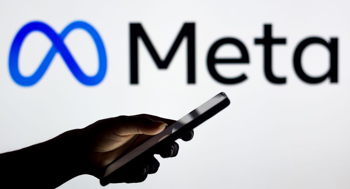 Meta logo behind person using their phone